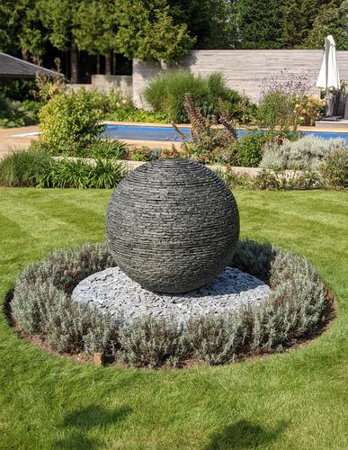 1m Grey Dry Sphere with loose slate chippings around the bottom and framed by hedging. A beautiful feature in this large garden in Woldingham