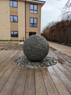 1m (Large) Rustic Slate Watersphere™ set on a circular bed of loose slate chippings cut out from the decking. De Wint Court, Lincolnshire. 