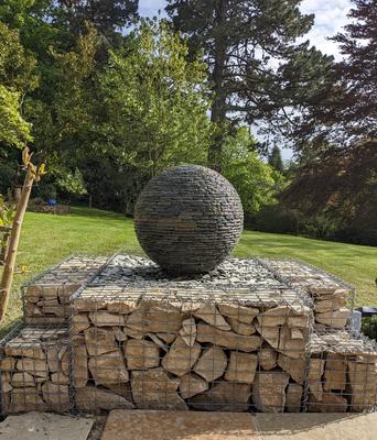 650mm (small) Rustic Watersphere™ raised up high and surrounded by a gabion basket. Merley House, Wimbourne.