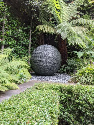 800mm (medium) grey slate Sphere set among Ferns in a courtyard garden in Notting Hill, London.