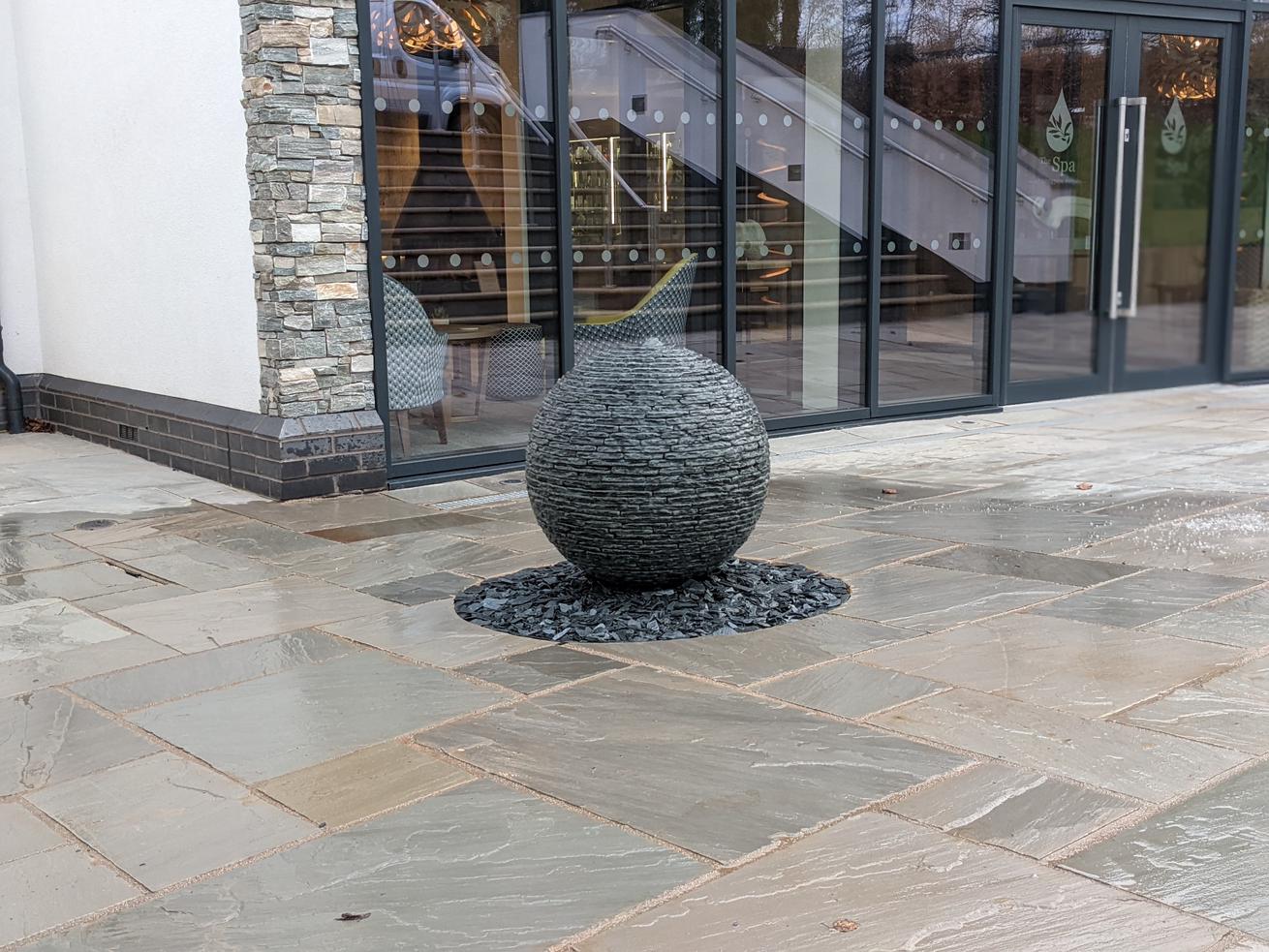 A Jeremy hastings 650mm grey slate ball water feature at the entrance of The Spa at Breedon Priory