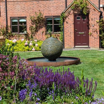 Jeremy Hastings 800mm rustic slate ball water feature on a Corten steel pool