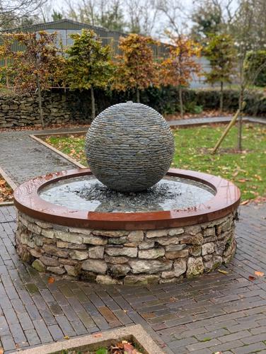Jeremy Hastings 800mm medium rustic slate ball water feature, on a shallow pool