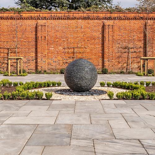 1m (large) Grey slate Watersphere™ set on a circular bed of slate chippings in an expansive walled garden.